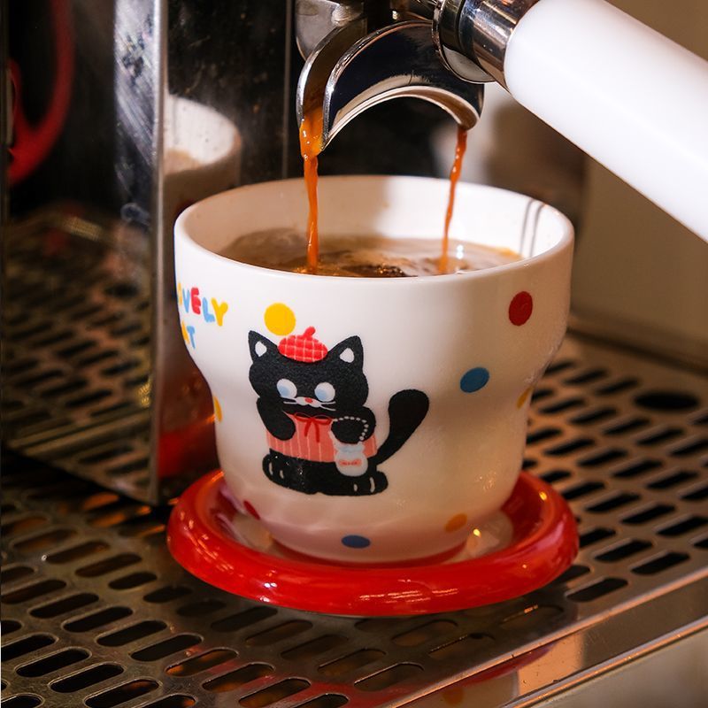 A red cat holding a coffee cup and saucer.