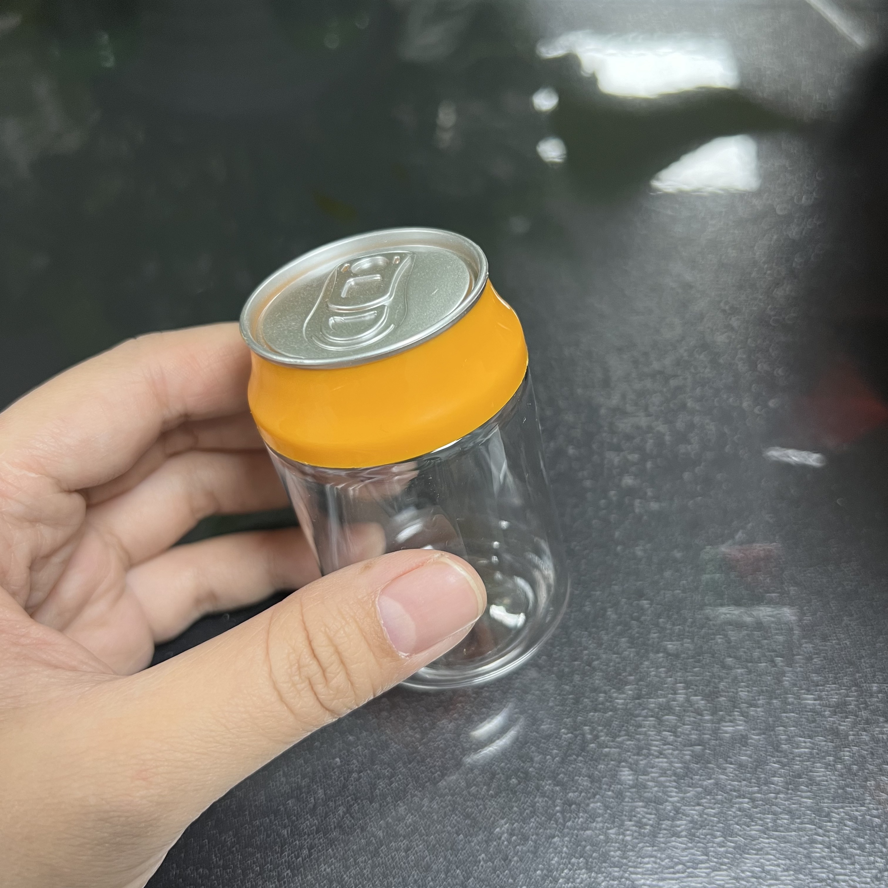 Botella transparente con tapa naranja (parte superior plateada)