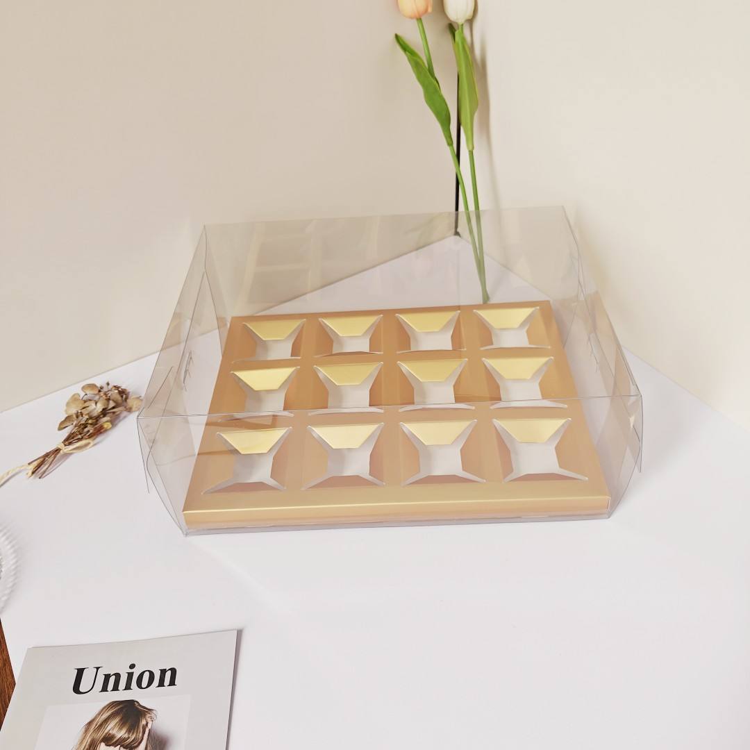 Boîte à gobelets en papier transparent, compartimentée en 12 sections dorées.