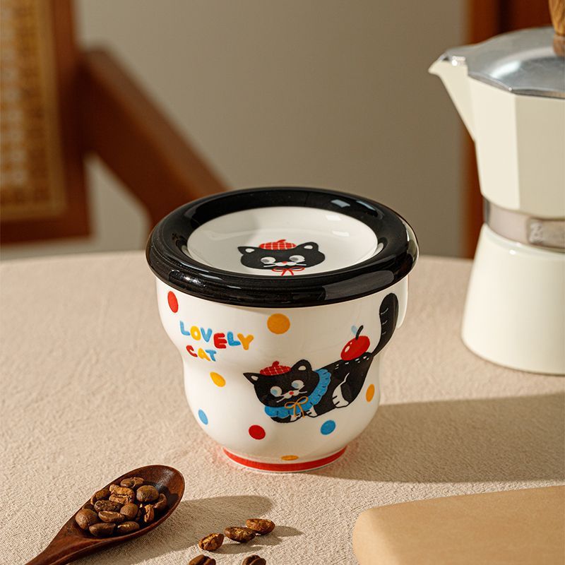 Black cat holding a coffee cup and saucer.