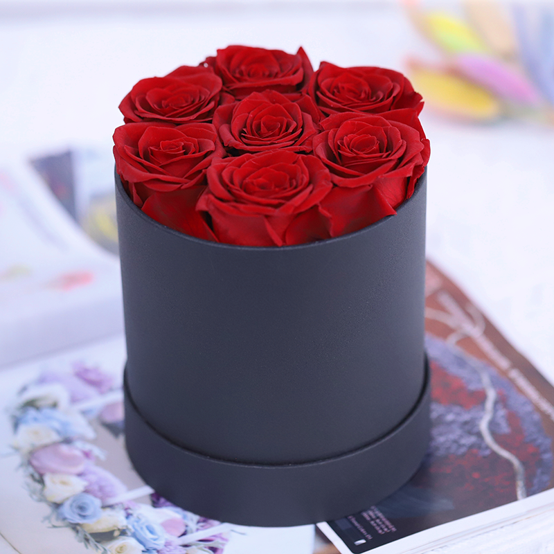 7 roses rouges dans une boîte ronde noire