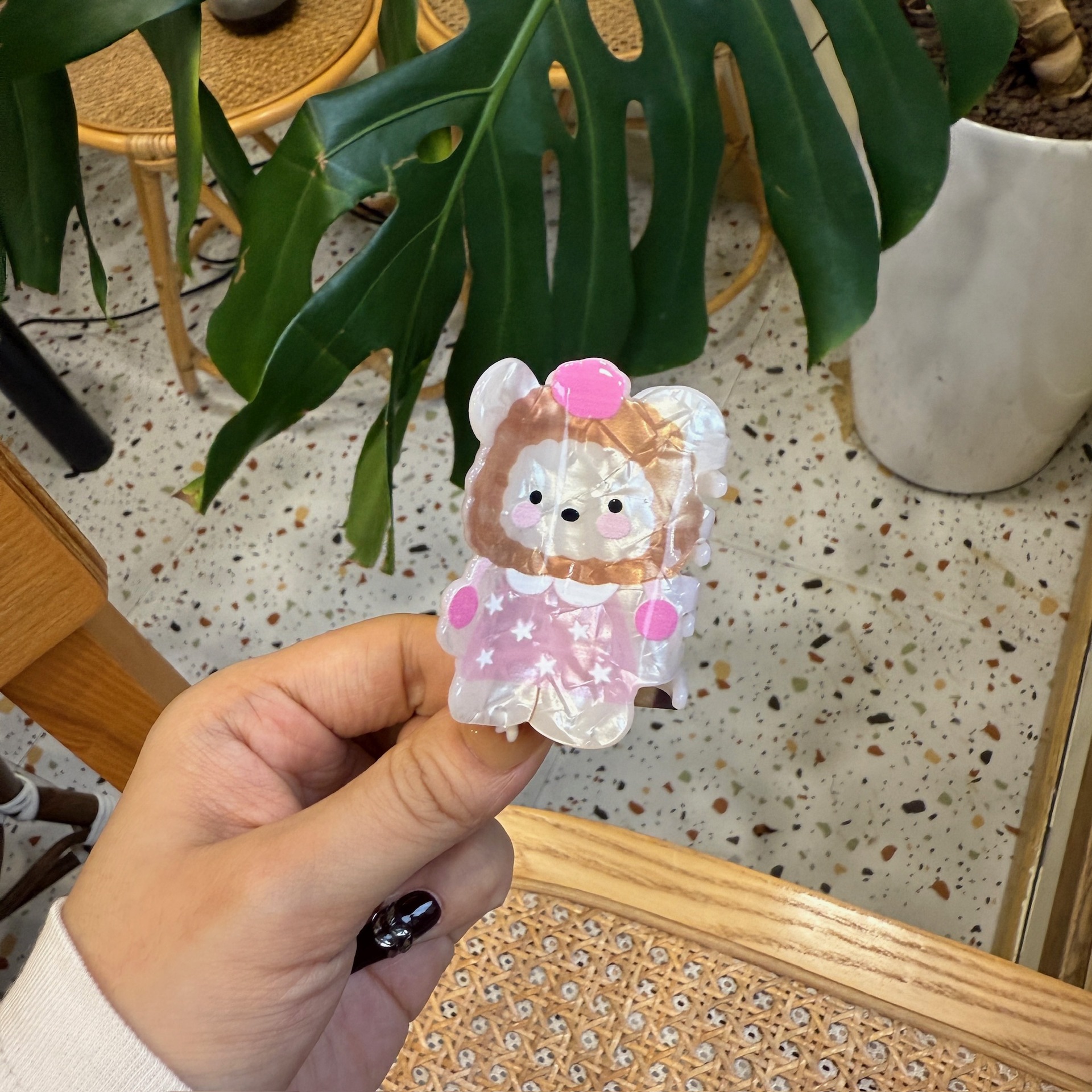 Ours en peluche avec un chapeau marron et des vêtements rose étoilé.