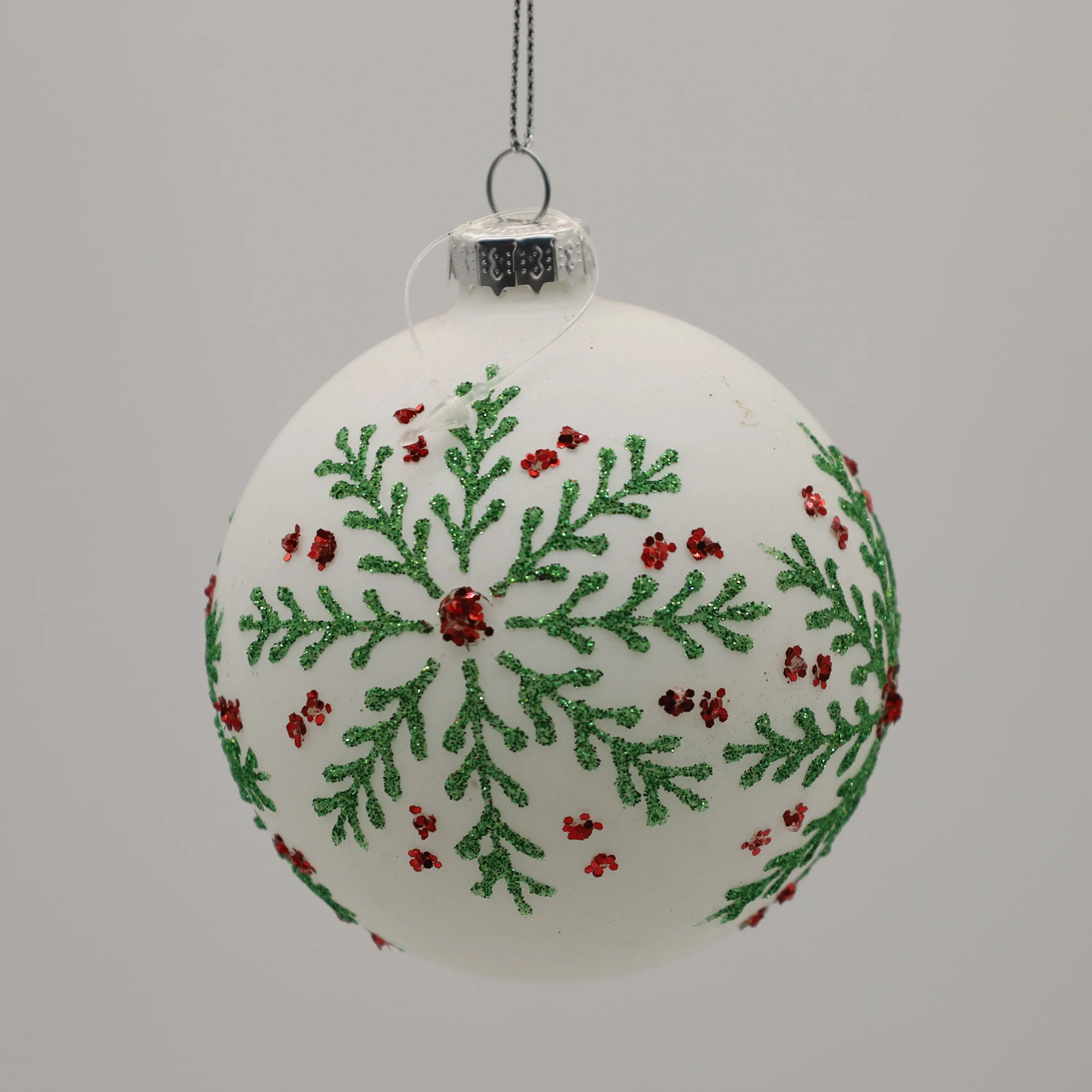 Arbre de noël décoré avec de belles feuilles vertes, accessoire en porcelaine argentée, flocons de neige dorés, boule de verre peint