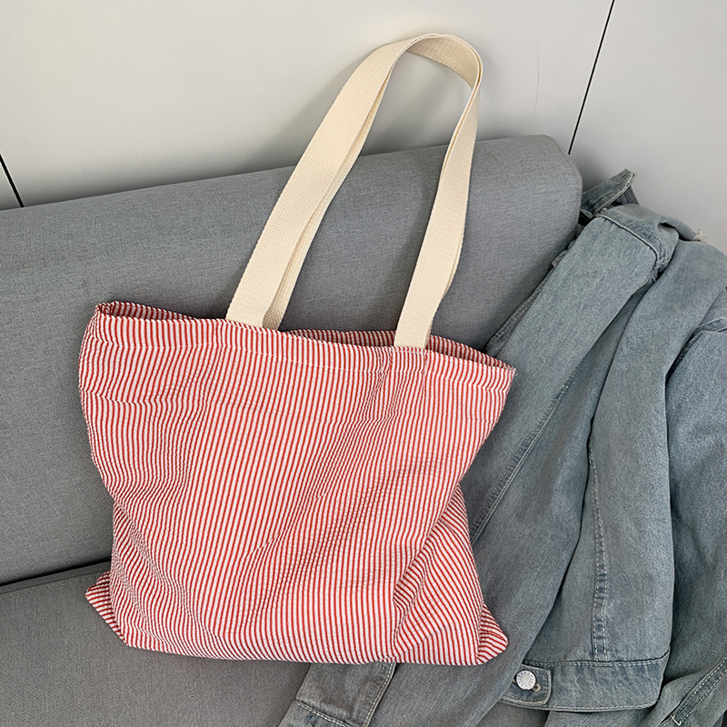 Correa de hombro beige con rayas rojas.