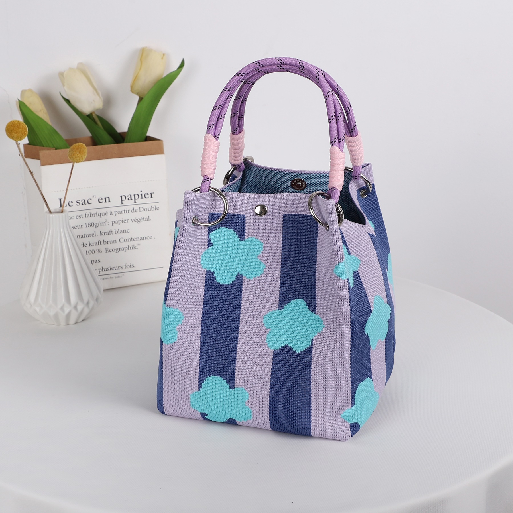 Sac à boucle avec rayures verticales et petites fleurs violettes et roses.