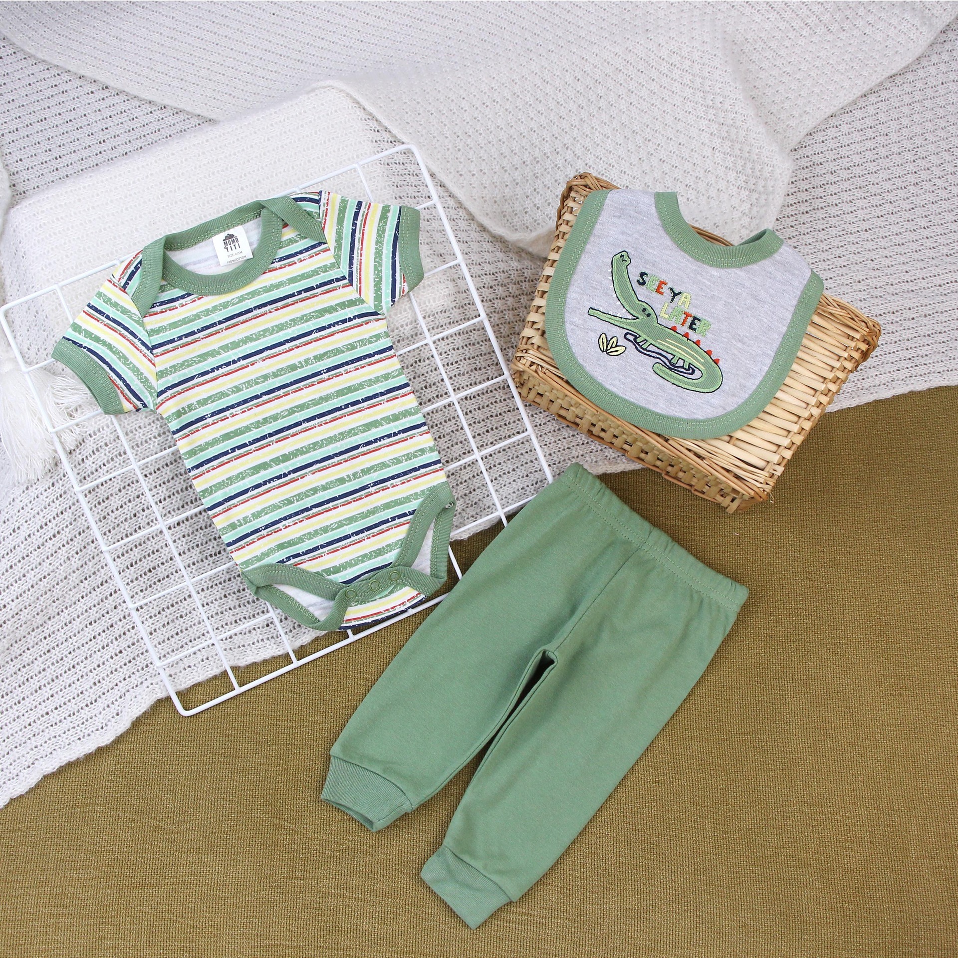 Ropa de bebé con estampado de cocodrilo verde y letras.