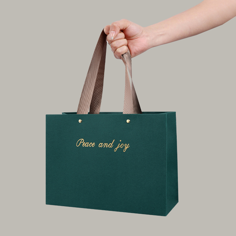 Bolsa de papel de pulpa de madera virgen verde oscuro con letras doradas en relieve.