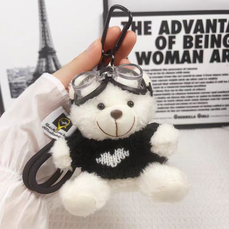 One white bear wearing glasses, black clothes, white heart, and black lanyard.