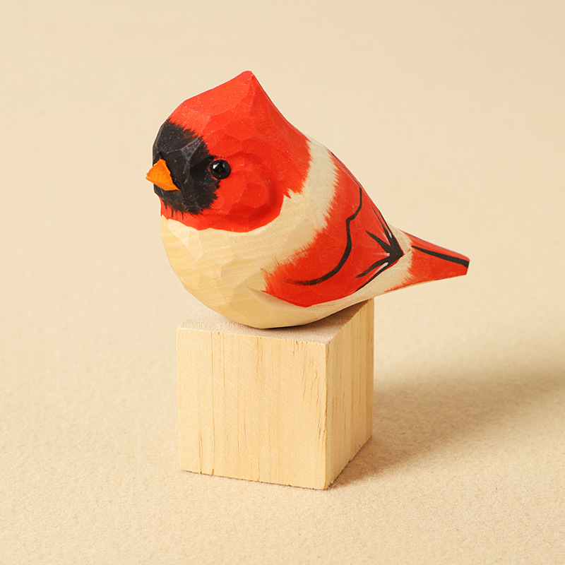 Bloc de bois sculpté représentant un oiseau à tête rouge.