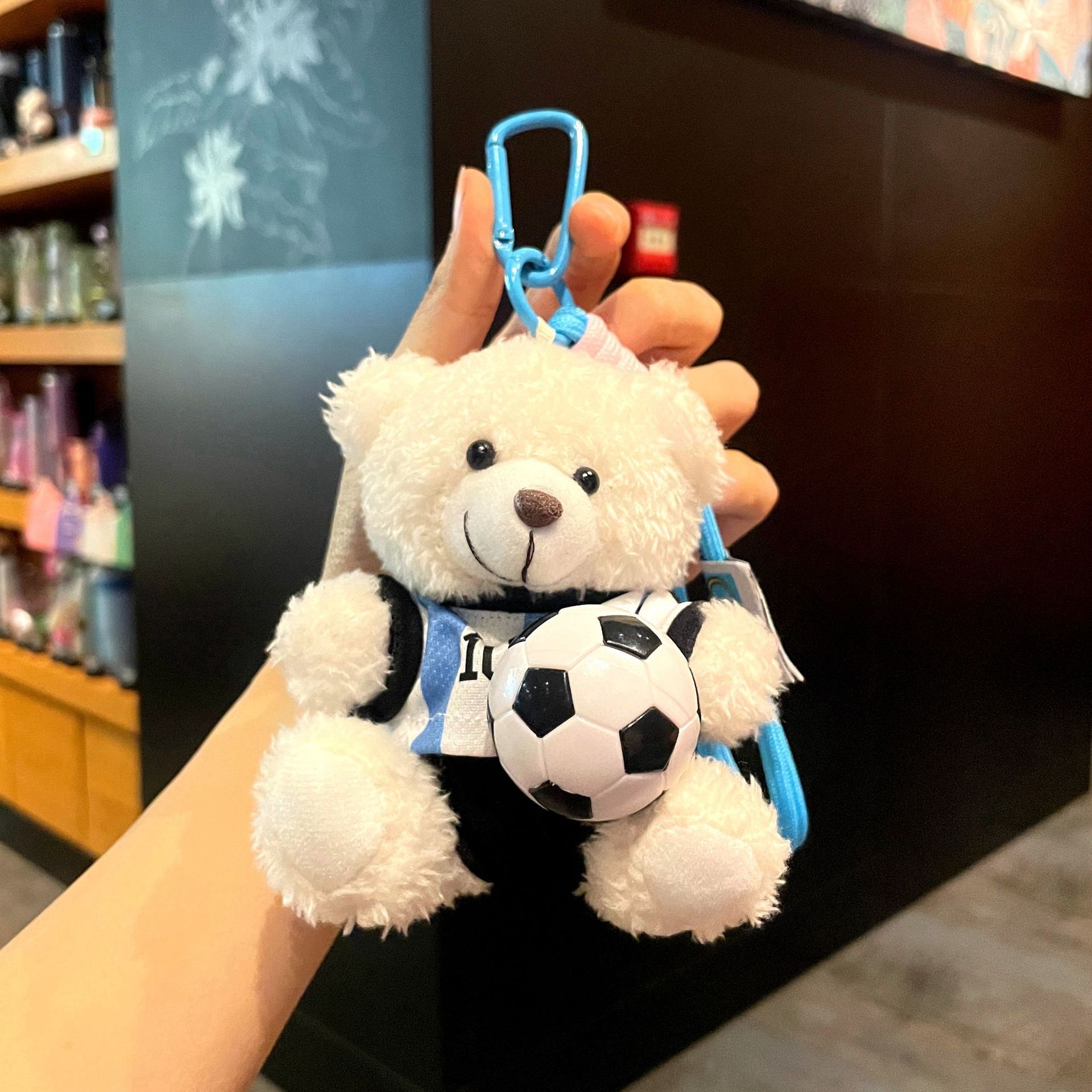 Messi, petit ours câlinant un ballon de foot noir et blanc.