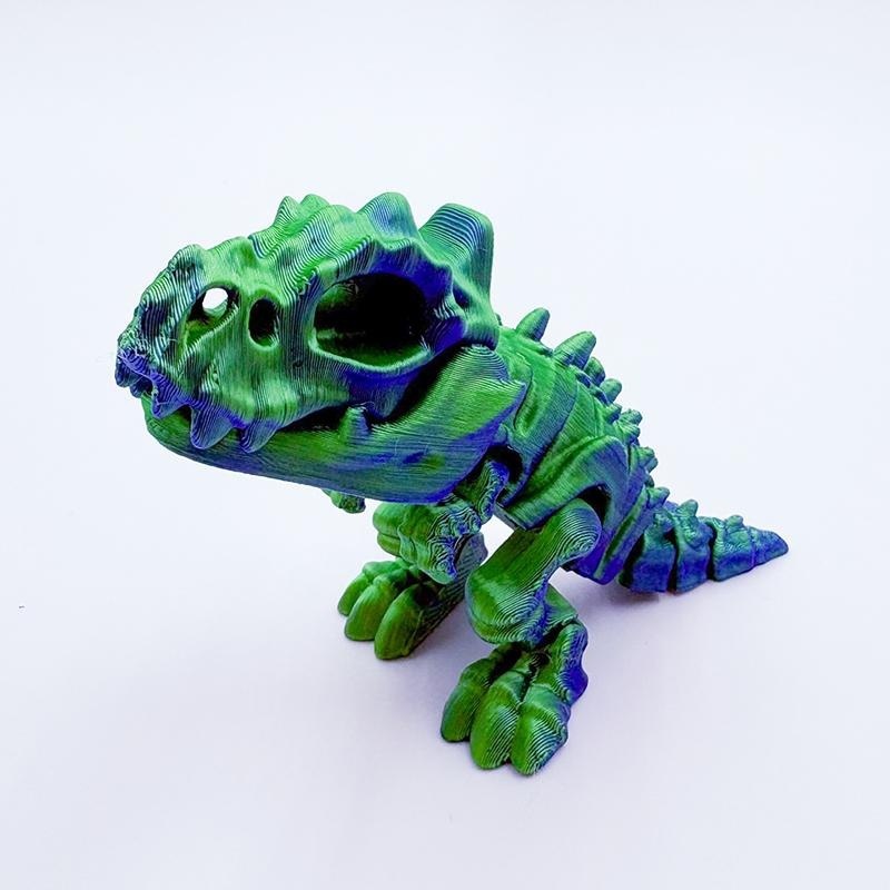 Bebé tiranosaurio azul verdoso de 11.5 cm que muerde la mano.