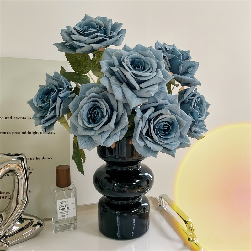 7 roses dans un vase bleu dans un vase en verre noir