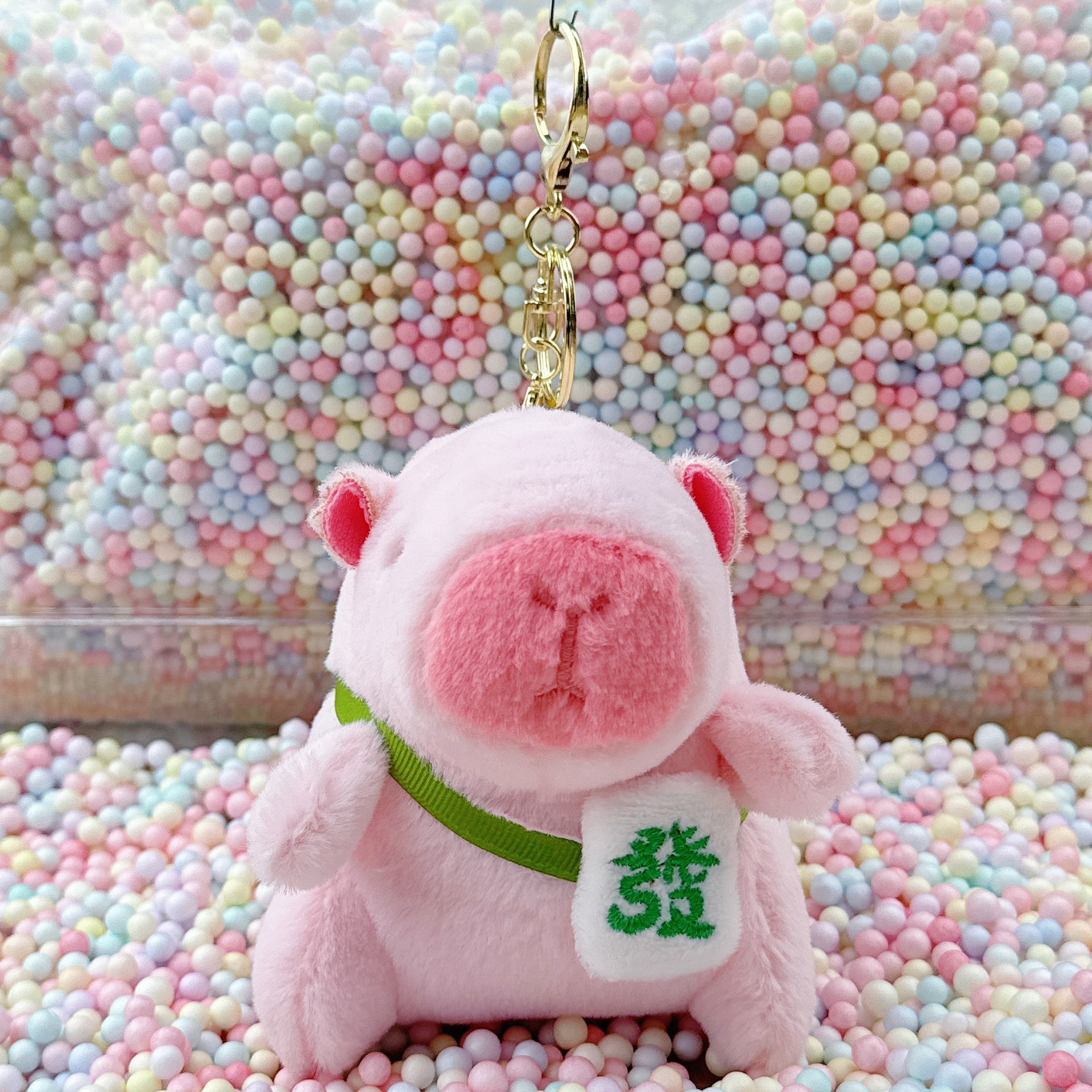 Amuleto de la suerte Kapibala rosa y verde con hebilla dorada.