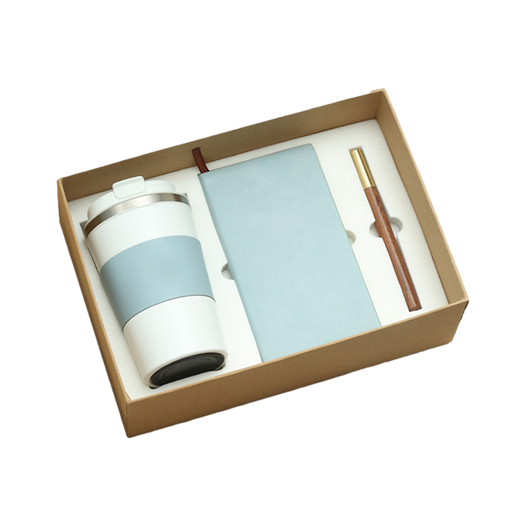 Vaso blanco + cuaderno azul + bolígrafo