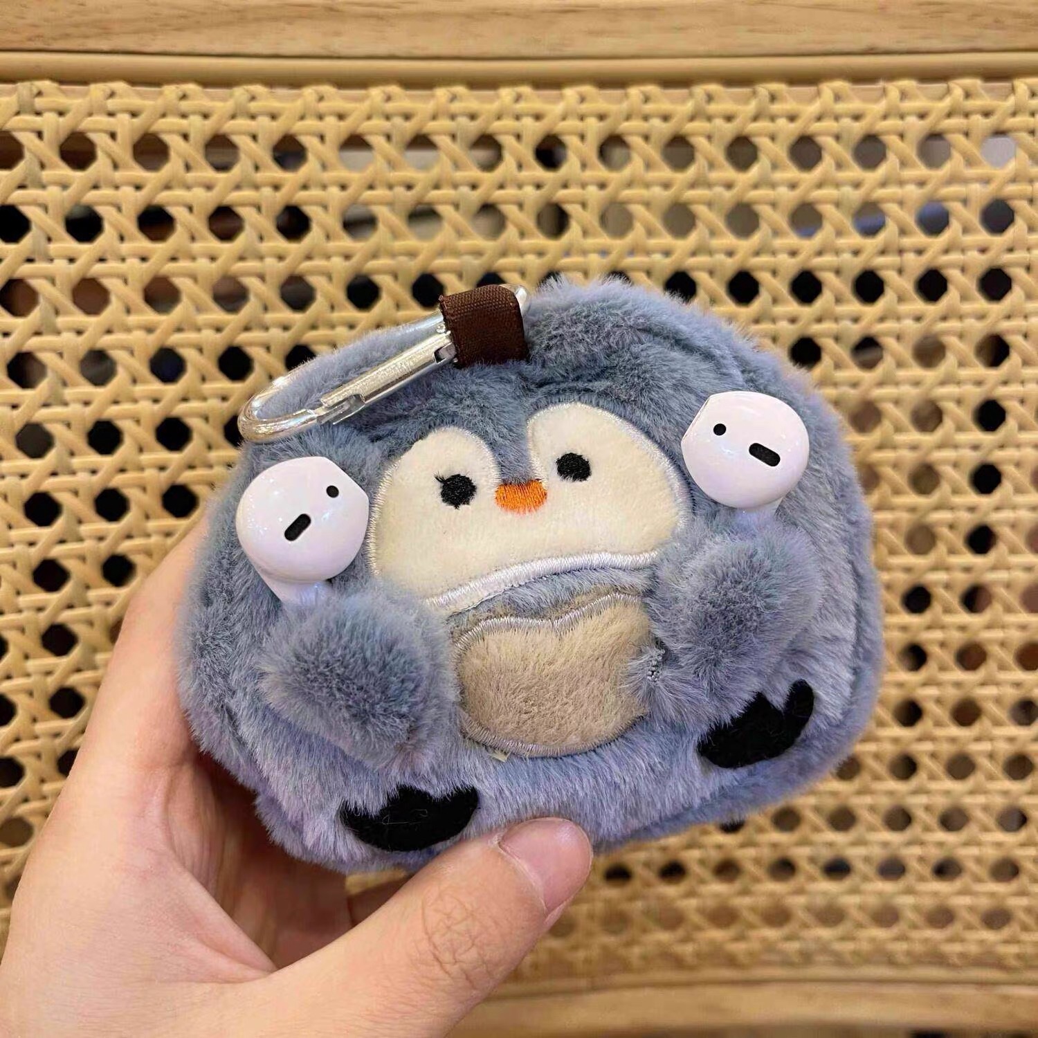 Étui pour écouteurs en forme de pingouin gris clair.