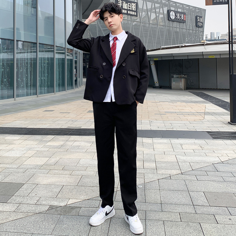 Blusa blanca de manga larga, pantalón negro, traje negro, corbata roja con corona.