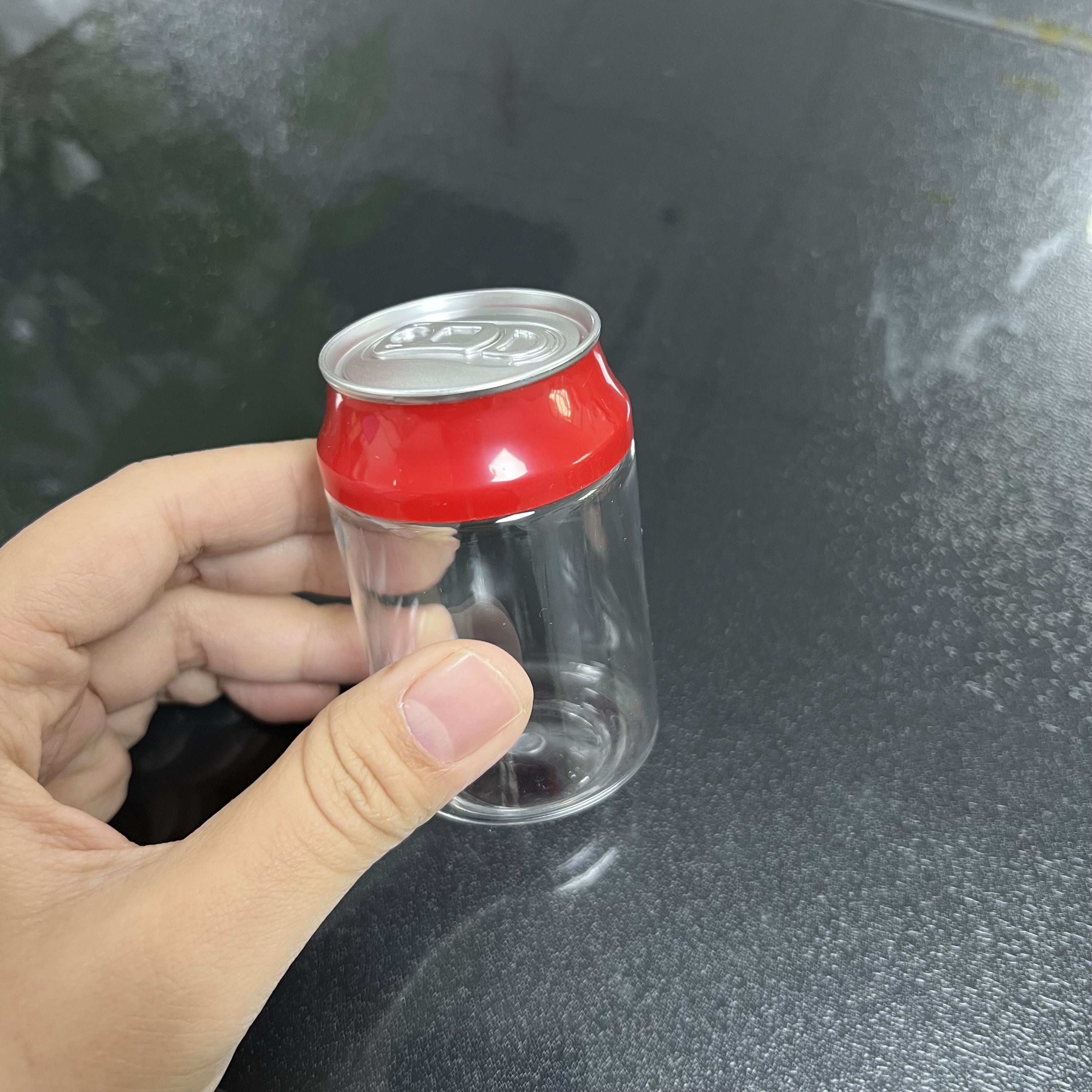 Botella transparente con tapa roja (parte superior plateada)