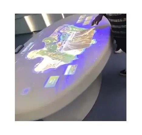 Mesa interactiva redonda con pantalla grande, mesas multitáctiles con proyección interactiva en exposición de negocios