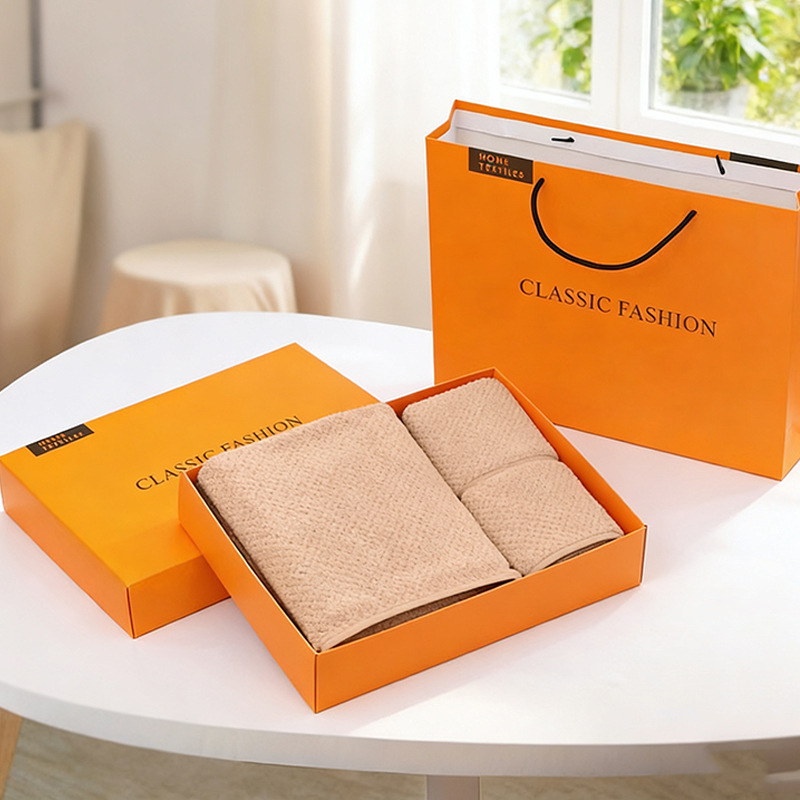 Caja de regalo marrón que contiene 2 toallas y 1 toalla de baño.