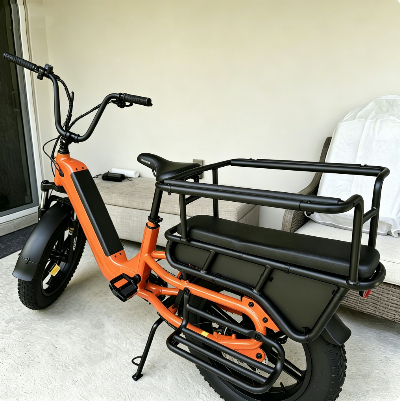 Vélo électrique orange avec coussin de siège arrière, barres de sécurité et repose-pieds.