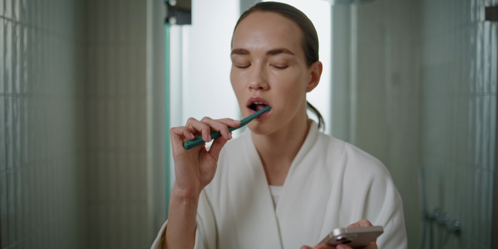 A woman cleaning teeth in the morning