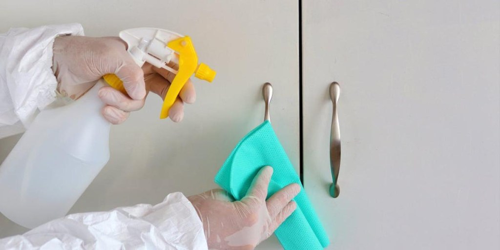Person Wearing Latex Gloves Disinfecting Cabinet Handles