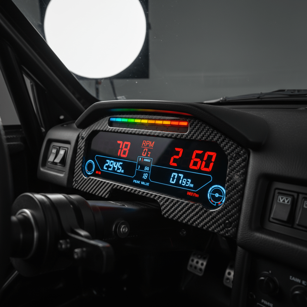 Advanced motorsport gauges with carbon fiber and LED lights in a racing cockpit.