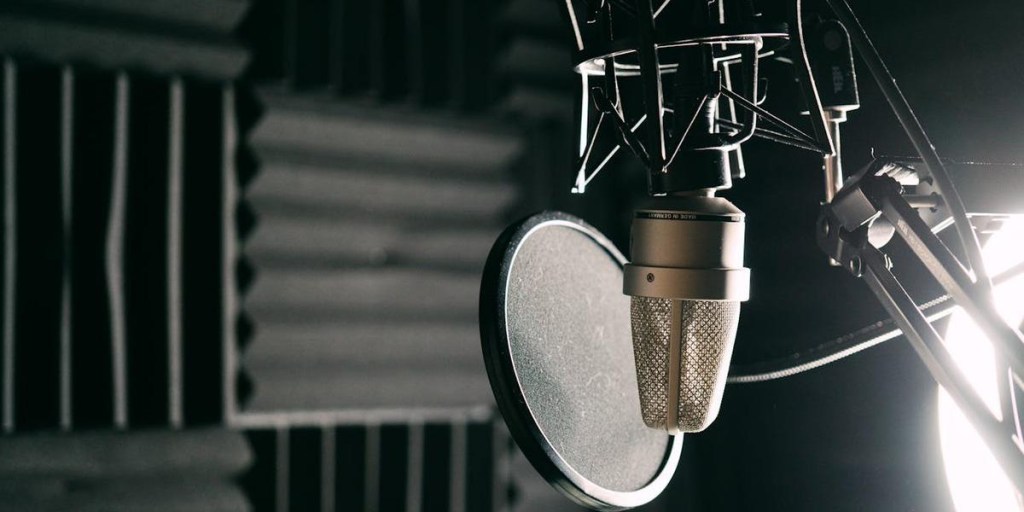 A professional recording studio microphone with acoustic foam panels background