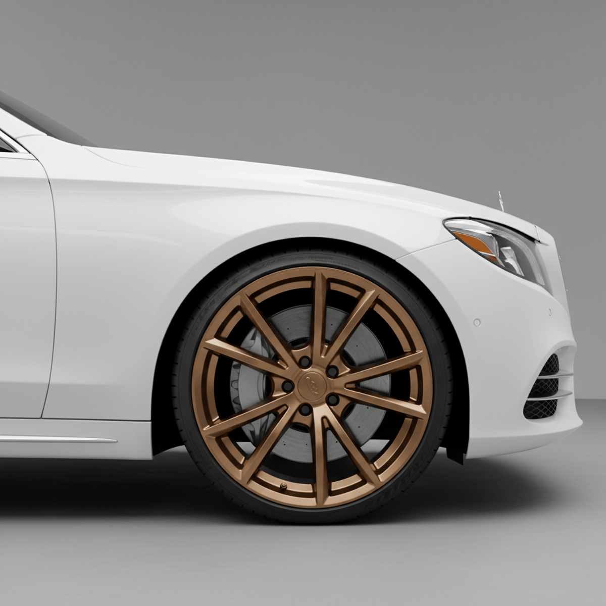 Close-up of a satin bronze monoblock wheel on a white luxury sedan.