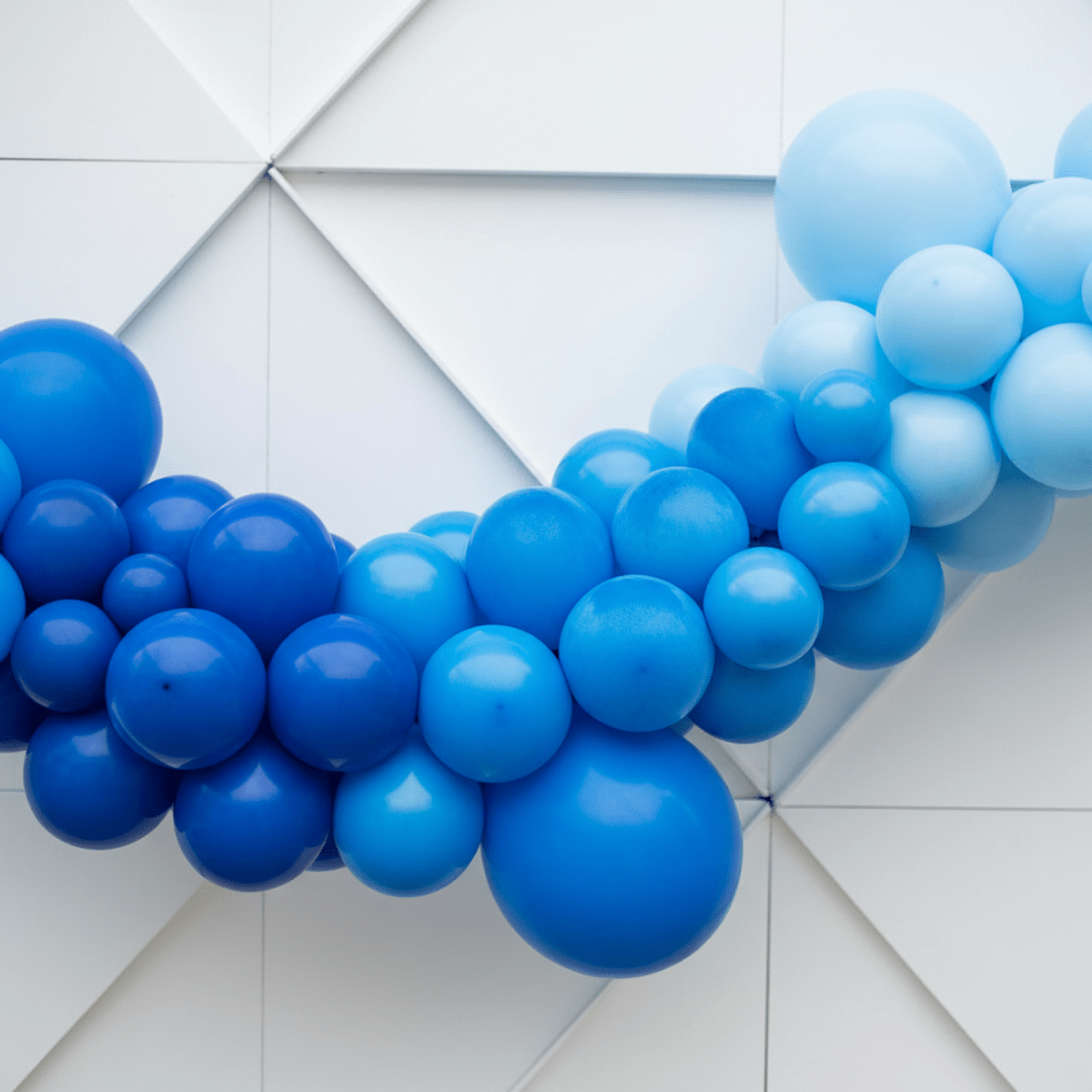 Monochromatic blue balloon garland with wave-like curves and varied surface textures.