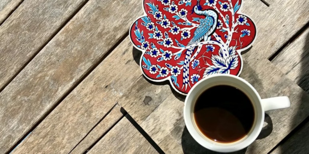 Cup of coffee besides a colorful coaster
