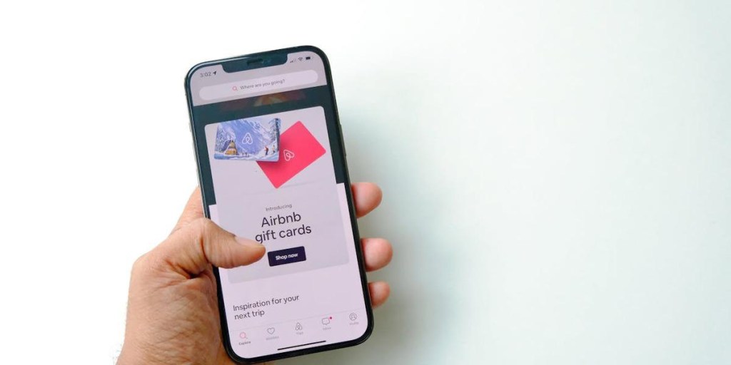 Person holding smartphone displaying Airbnb gift cards page