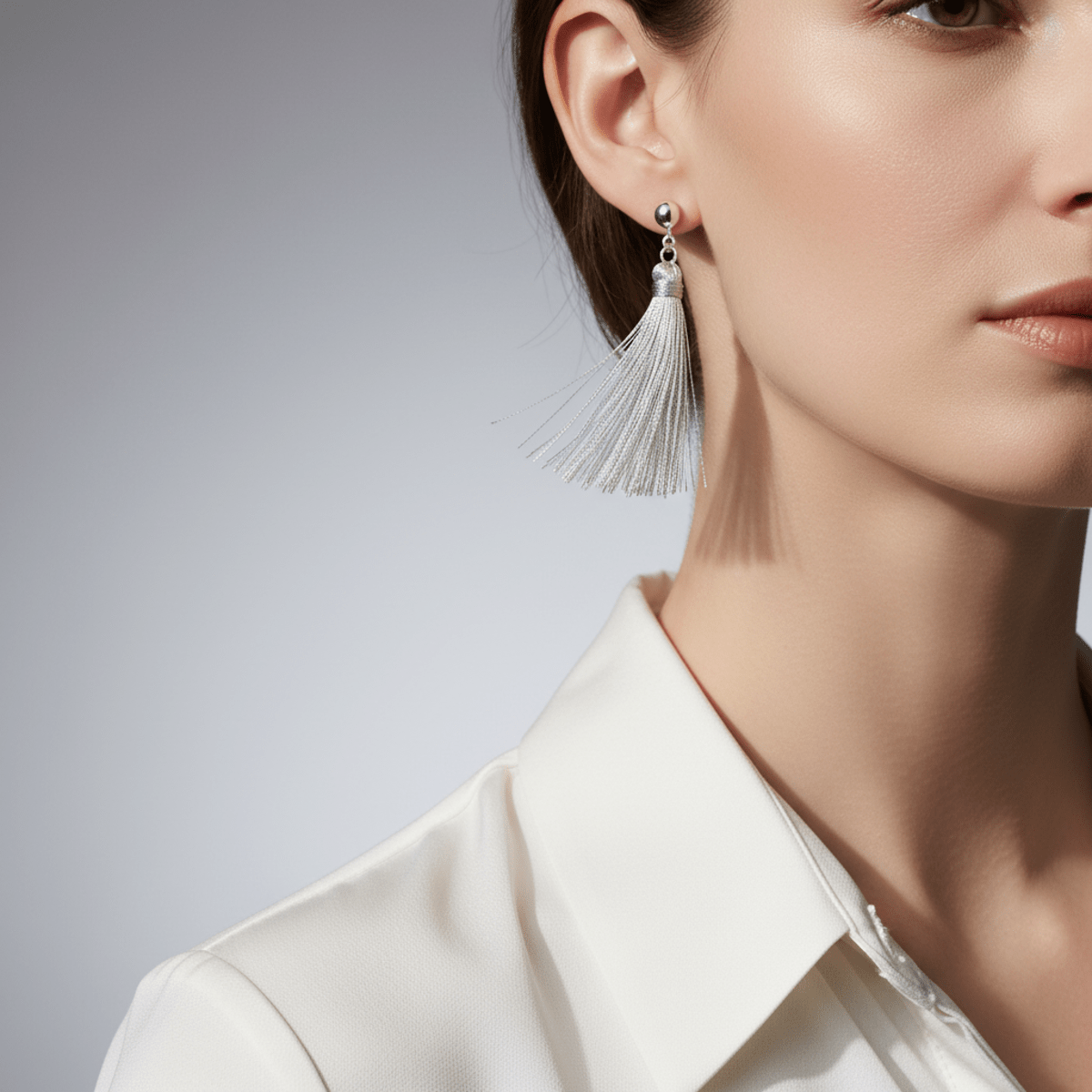 Model wears delicate silver micro-tassel earrings with fine wire and subtle thread texture.