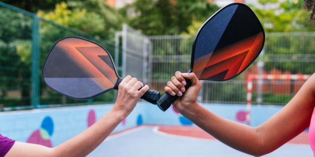 People tapping pickleball paddles