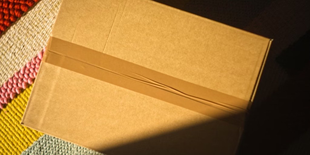Package box tapes shut on a rug