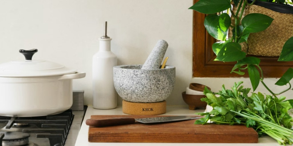 Mortar and pestle on kitchen counter behind a cutting board