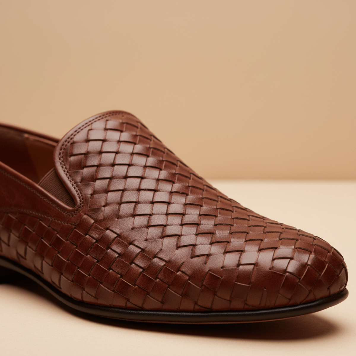 Close-up of hand-woven leather slip-on shoes with basket-weave texture.