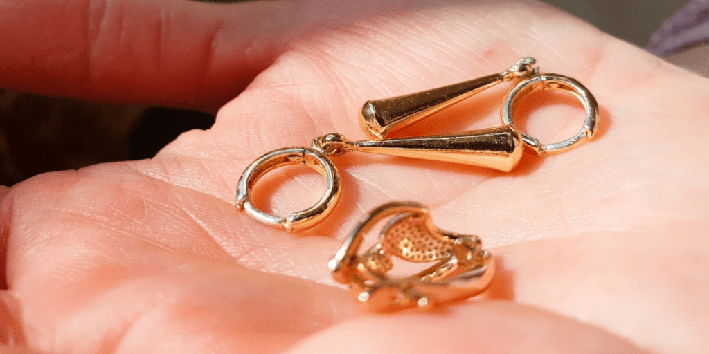 Person holding gold earrings