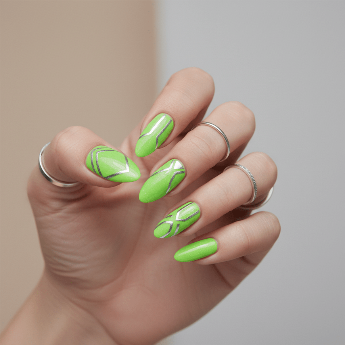 Sleek almond nails with neon green polish and metallic silver geometric accents.