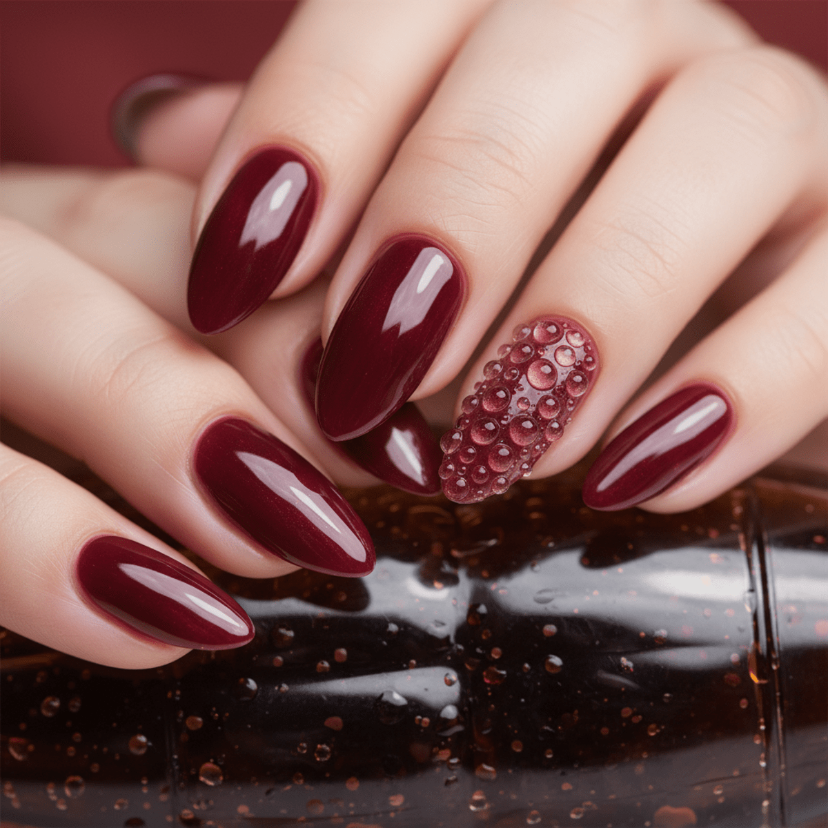 Close-up of glossy burgundy nails with 3D gel bubbles resembling fizzy soda.