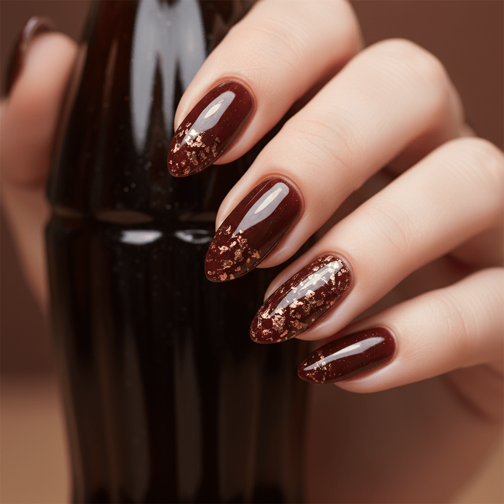 Close-up of glossy cherry cola nails with embedded gold flakes on slender hands.
