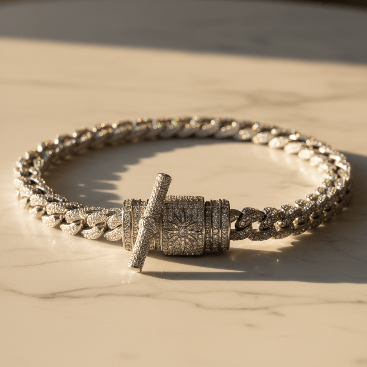 Iced-out moissanite chain with engraved patterns on a marble surface.