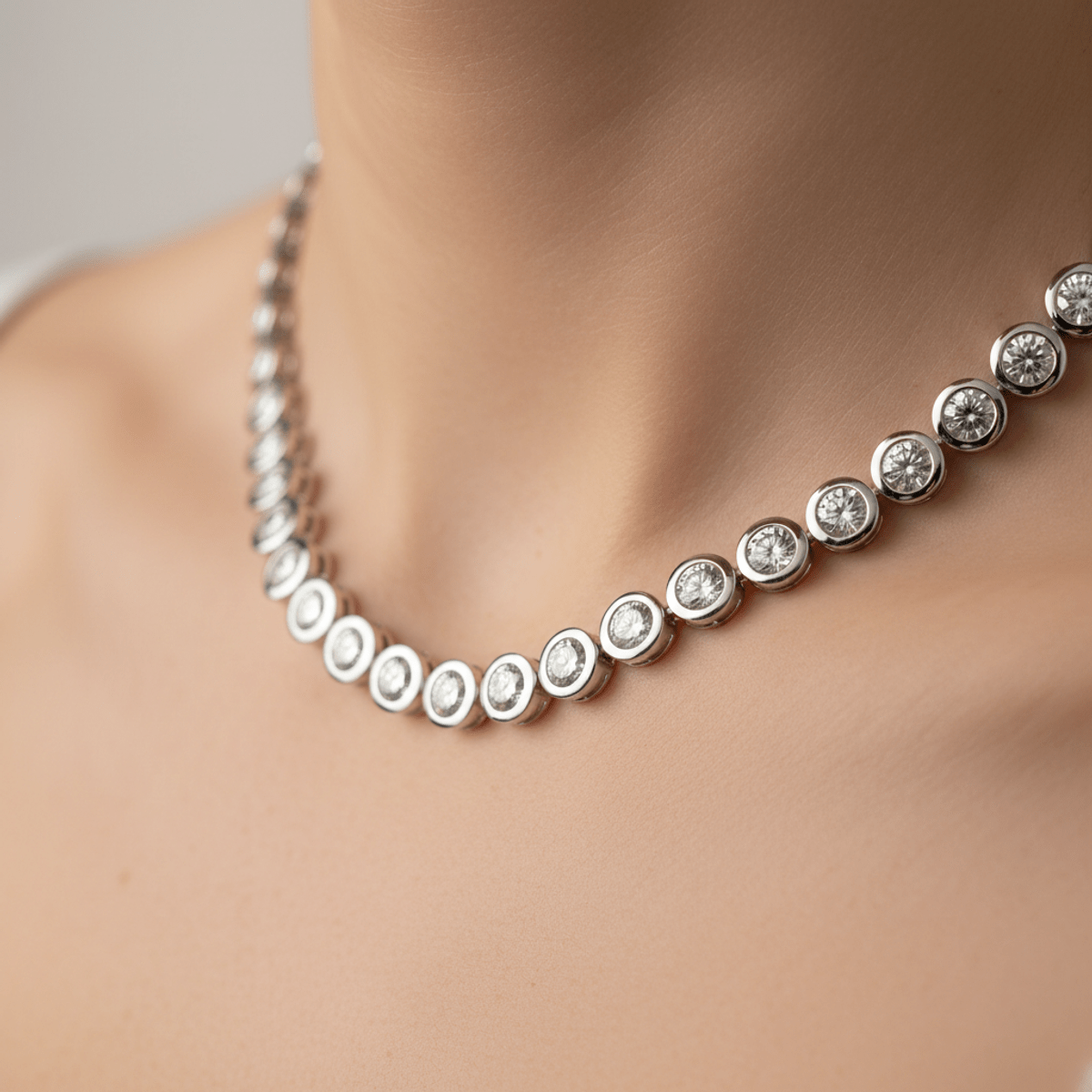 Sleek bezel-set diamond chain with a fluid, snakeskin-like curve and polished metal rims.