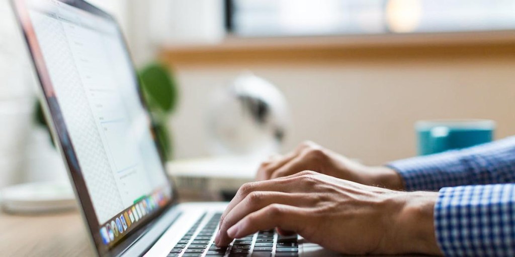 Person typing on a MacBook laptop at a desk