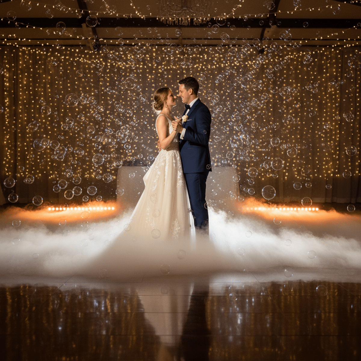Bride and groom first dance in fog with iridescent bubbles and warm uplighting.