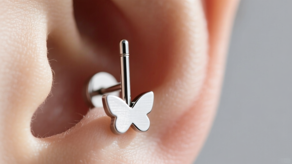 Close-up of a 20-gauge titanium stud earring on an earlobe, showing the thin post and flat butterfly backing in soft daylight