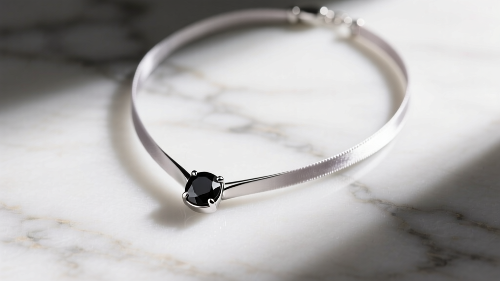 Overhead view of a modern minimalist thali necklace crafted in brushed platinum with a single black diamond accent on a silk cord.