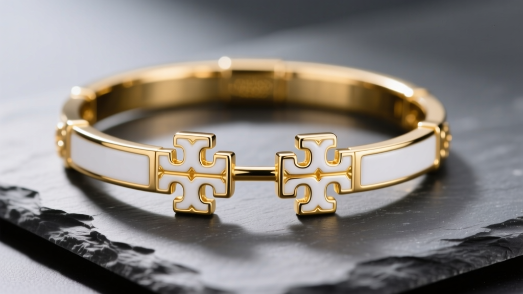 Gold Tory Burch Double-T studs on slate, showing crisp white enamel and bright gold-plated edges under soft studio lighting.