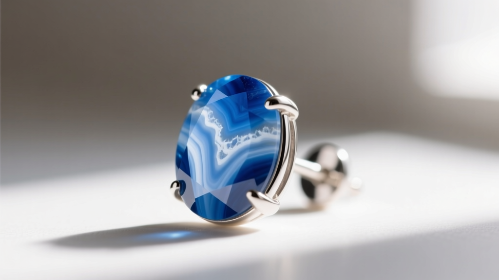 Macro shot of cabochon blue lace agate in an 18g sterling silver stud earring, highlighting intricate white banding patterns.