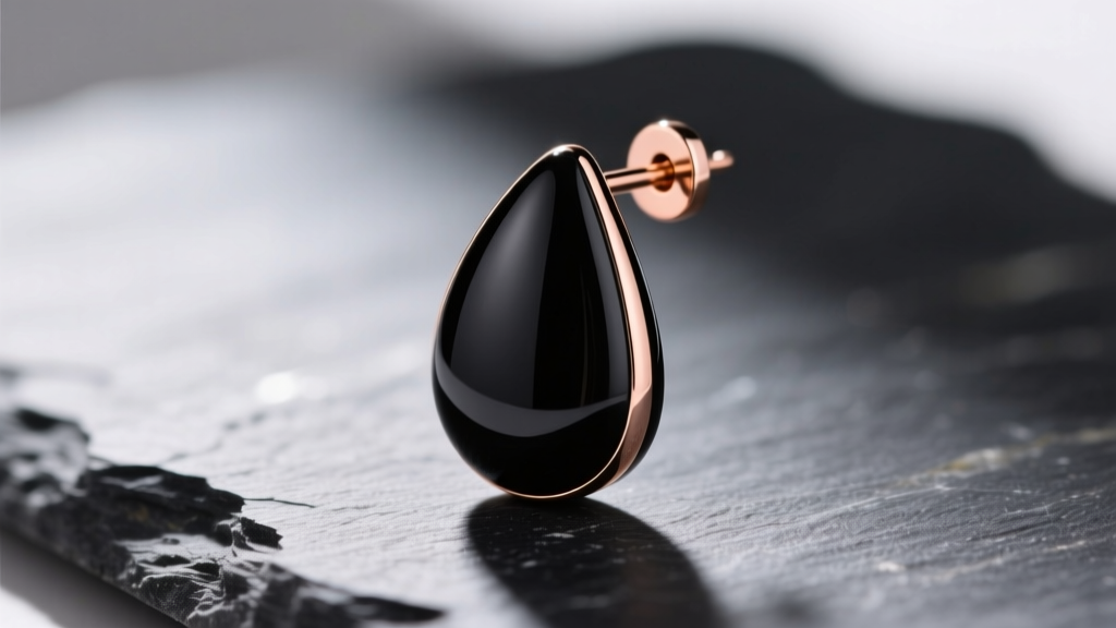 Macro shot of a sleek black ceramic drop earring with subtle rose gold charging contacts resting on dark slate stone